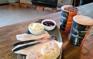 Scones with jam and cream infront of wood fire